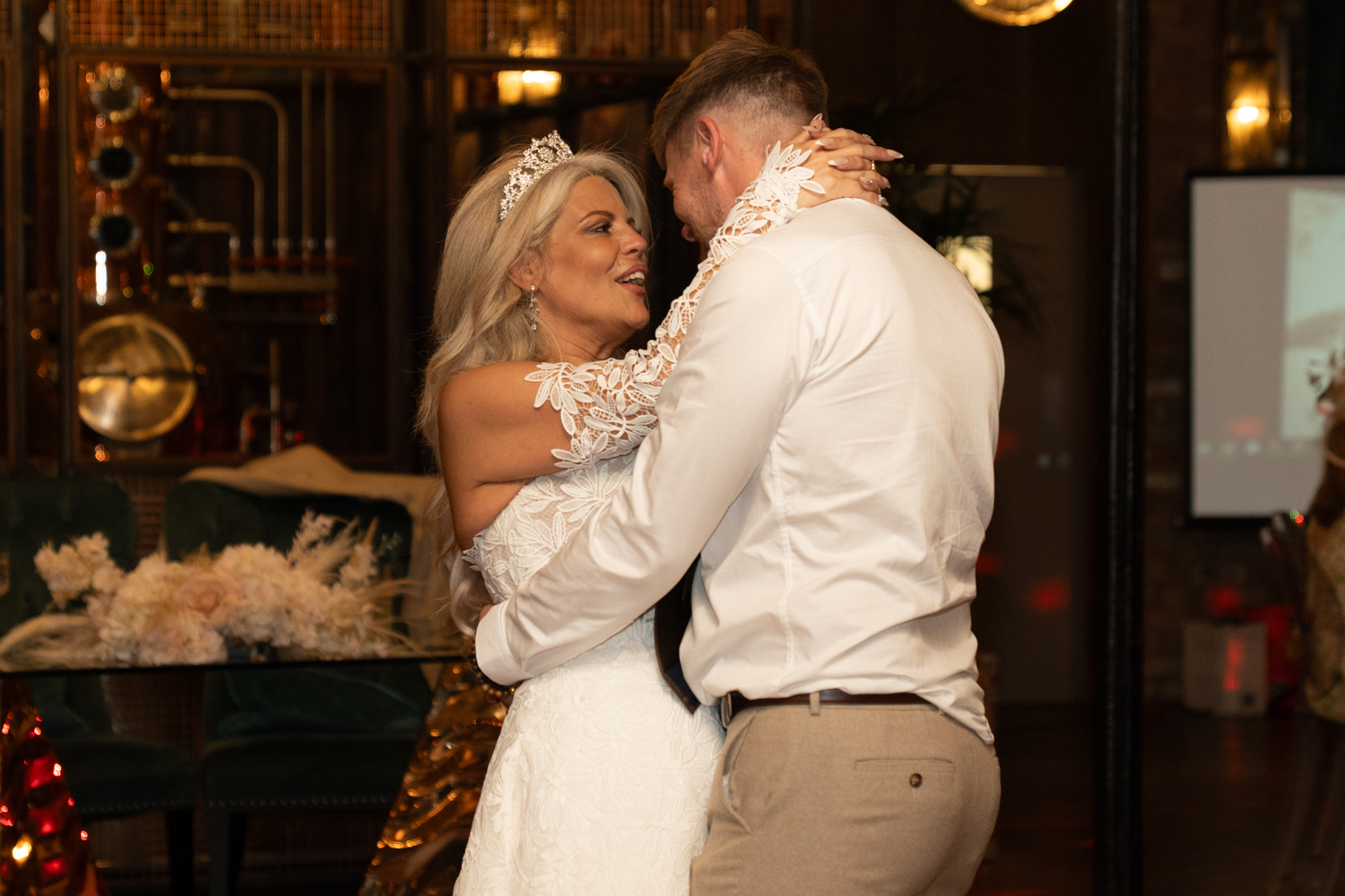 A close-up of the couple during their first dance — the bride smiling, her hand on his neck, completely lost in the moment